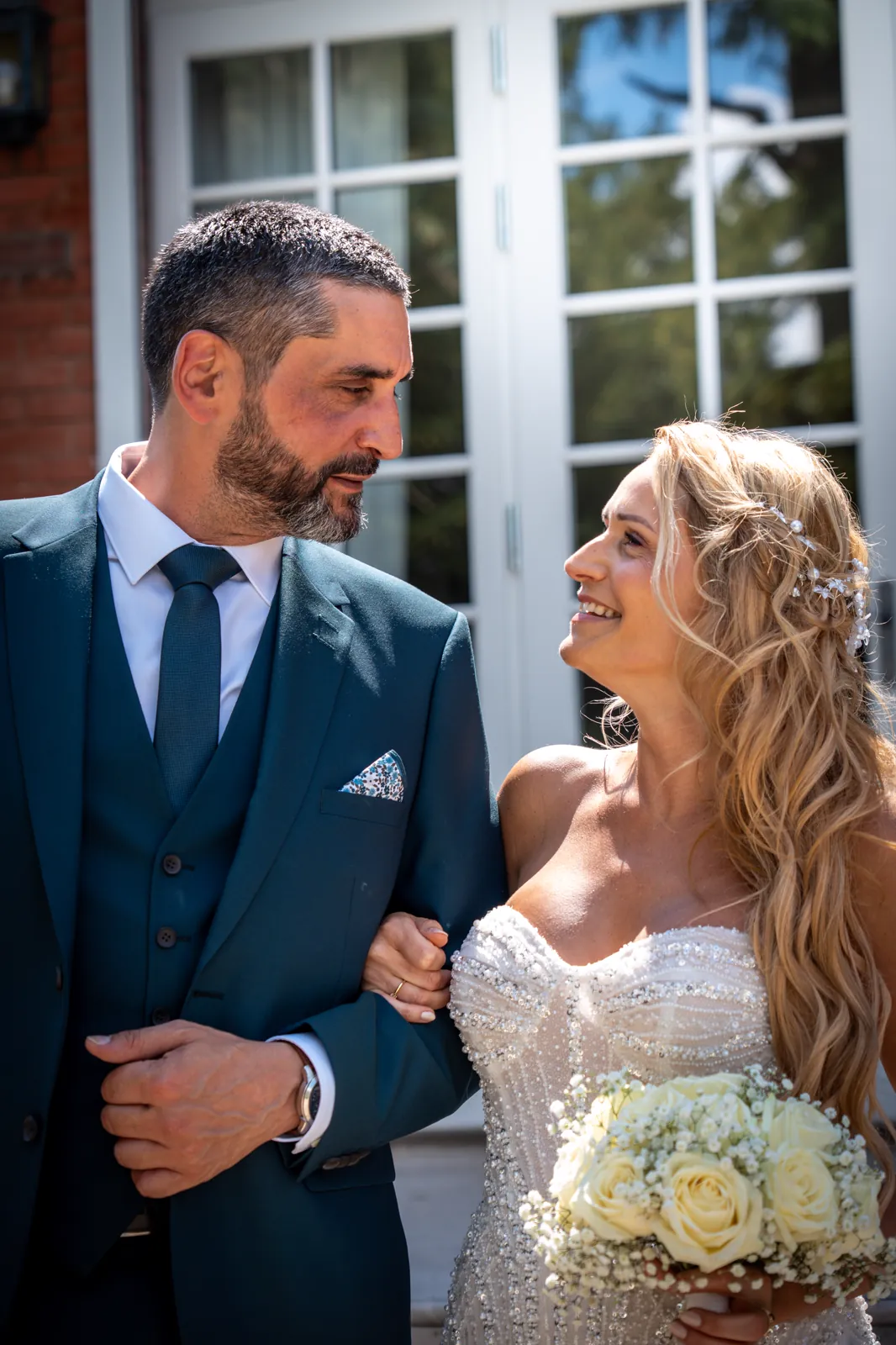The newlyweds face to face in front of the house, on their wedding day