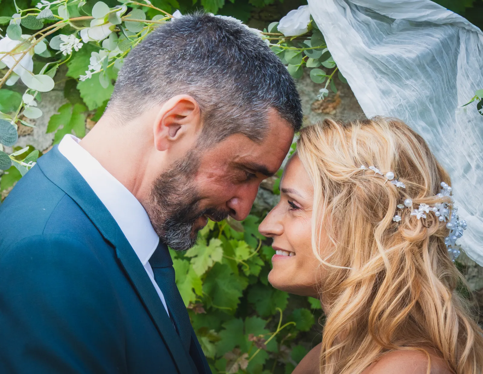 The newlyweds forehead to forehead under the vines